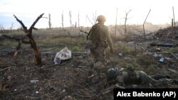 A Ukrainian soldier passes by the body of a dead Russian soldier in Andriyivka in the Donetsk region in September.