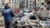 A war crimes prosecutor stands next to destroyed cars in the courtyard of a damaged residential building following a missile attack in Myrnohrad, Donetsk region, Ukraine, on March 10.