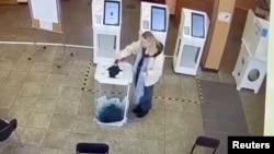 A woman pours a liquid into a ballot box during the Russian presidential election in Moscow on March 15.