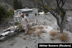 Sultan Ali, 70, walks over cracks that developed after a GLOF swept away part of the land in Hassanabad.