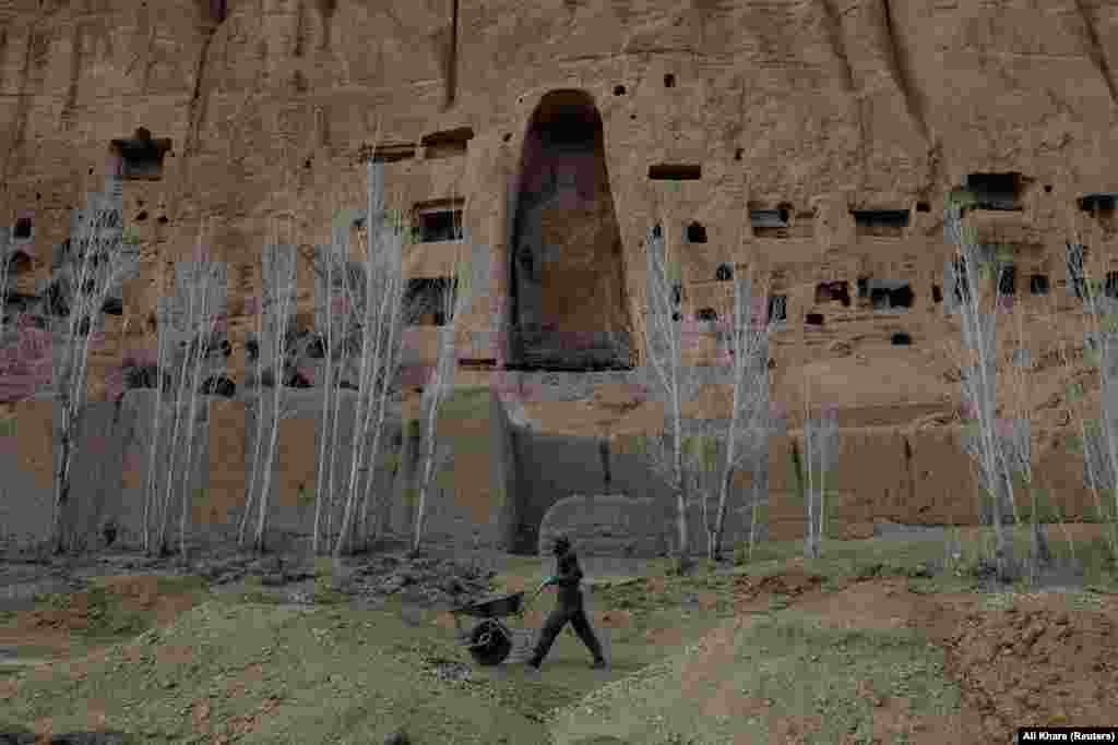 An Afghan worker pushes a wheelbarrow under the empty space where a 1,400-year-old Buddha statue once stood in Bamiyan, Afghanistan. Archaeologists working to preserve what little cultural heritage is still present in the Bamiyan Valley have been dealing with illegal excavations, encroaching developments, and Taliban gunmen who use the remnants of the Buddhas for target practice.