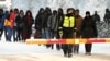 Finnish border guards escort migrants at the border crossing with Russia at Salla, northern Finland, on November 23.