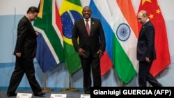 Chinese President Xi Jinping, South African President Cyril Ramaphosa, and Russian President Vladimir Putin arrive to pose for a group picture during the 10th BRICS summit in July 2018 in Johannesburg, South Africa.