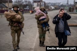 Украинские военные несут детей, помогая эвакуироваться бегущей от войны семье. Окраина Киева, 5 марта 2022 года