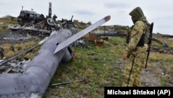 A Ukrainian soldier inspects a damaged Russian military helicopter on Snake Island, in the Black Sea, on December 18, 2022.