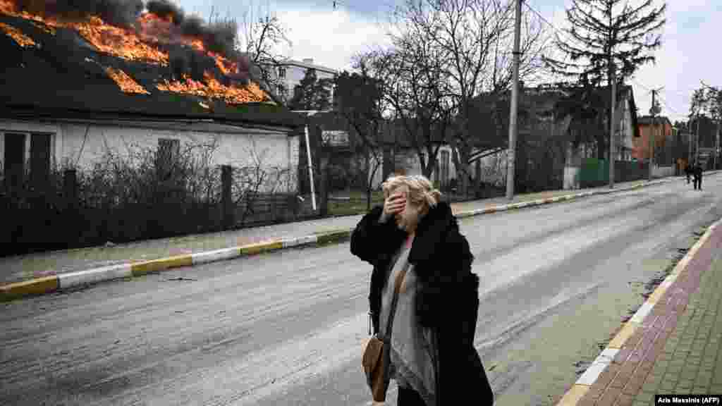 Ukraine -- A woman reacts as she stands in front of a house