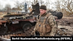 Украинский военнослужащий возле уничтоженного российского танка Т-72 в освобожденном селе Лукьяновка Киевской области, 27 марта 2022 года