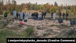 Police and forensics experts examine a mass grave found in the Donetsk region of Ukraine in October 2022.