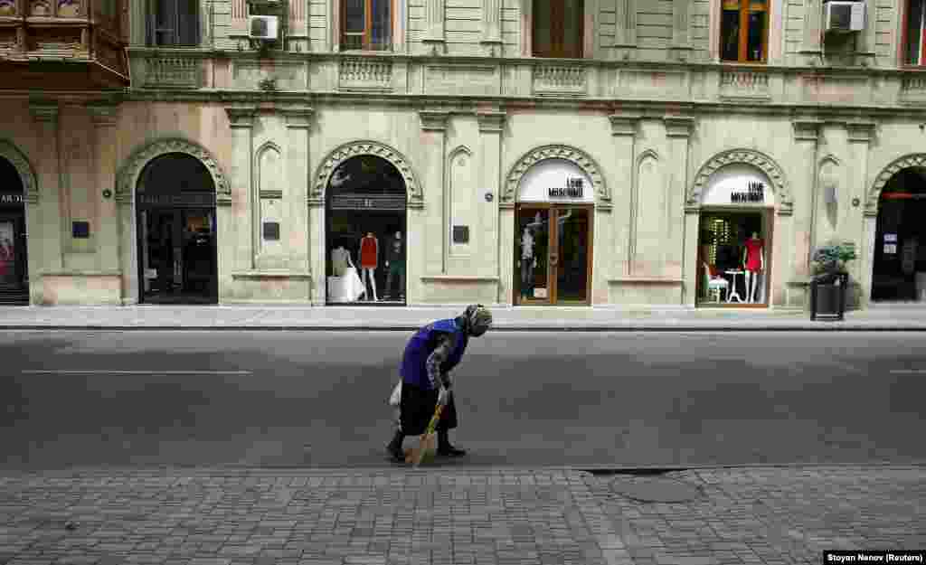 A woman sweeps a street in front of fashion boutiques in Baku.&nbsp;