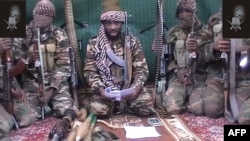 A man claiming to be the leader of Nigerian Islamist extremist group Boko Haram, Abubakar Shekau, is seen in this video from September 2013 flanked by armed men. 