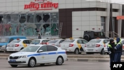 Police officers stand guard in front of a damaged store at the scene of fresh aerial attacks on Belgorod, Russia, on March 14.