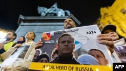 People hold portraits of late Russian opposition leader Aleksei Navalny at candlelight vigil in downtown Zagreb on February 23.