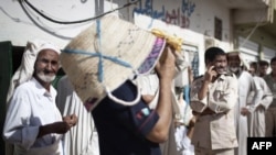 Residents of Zintan, the rebel stronghold on the Western Libyan front, queue outside one of the few open bakeries to collect loaves of bread