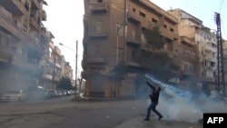  A protester throws a tear gas bomb back towards security forces in the flashpoint city of Homs.