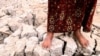 IRAQ -- An Iraqi girl stands on dry, cracked earth in the marshes area near the al-Fuhood village, north of the southern city of Basra, (Al-Basrah), 01Oct2008. Iraq has been suffering from drought for two years.