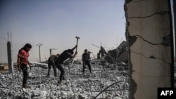 Syrians clear up the rubble of their houses that were destroyed during clashes on the outskirts of Raqqa.