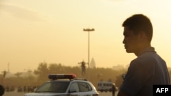 A plainclothes policeman keeps watch on Tiananmen Square at sunrise in Beijing.