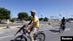 Libyan National Transitional Council fighters ride on bicycles to get to the front line in the center of Sirte on October 12.