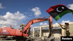 A boy waves a flag as an excavator demolishes walls of the residence of Muammar Qaddafi at the Bab al-Aziziyah complex in Tripoli on October 16.