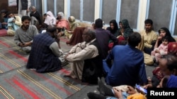 Passengers who were rescued from a train after it was attacked by separatist militants sit at the Mach Railway Station in Pakistan on March 11.