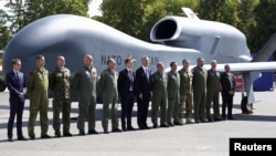 NATO Secretary-General Jens Stoltenberg (center) with officials and military personnel in front of a NATO drone outside the venue of the Warsaw Summit.