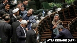 An Iranian lawmaker uses a phone to take a "selfie" picture as EU foreign-policy chief Federica Mogherini walks by in parliament in Tehran on August 5.