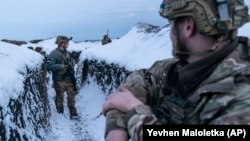 Ukrainian servicemen walk along a snow-covered trench at the front line near Vodiane in eastern Ukraine on March 5.