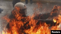 A riot policeman falls after being hit with a Molotov cocktail in Athens.