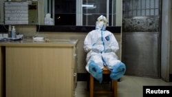 A medical worker in a protective suit takes a break during her night shift at a community health service center in Wuhan. 