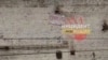 A banner reading "Save Us" hangs from a brick prison wall.