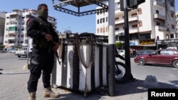 A member of the Syrian security forces stands guard after hundreds were killed in deadly violence in Latakia.