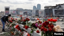 A woman lays flowers near the Crocus Concert Hall near Moscow, where a deadly shooting attack killed more than 140 people. 