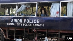 A police officer inspects a damaged police bus at the site of a bomb attack in Karachi on February 13.