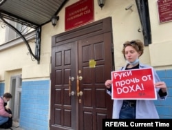 A single protester, as allowed by law, demands "hands off Doxa" outside the court in Moscow.