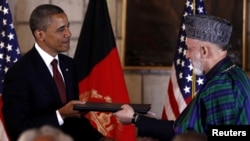 Afghan President Hamid Karzai (right) and his U.S. counterpart Barack Obama exchange documents after signing a Strategic Partnership Agreement at the Presidential Palace in Kabul on May 2.