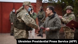 Ukrainian President Volodymyr Zelenskiy (right) shakes hands with a serviceman in the town of Zolote in the Luhansk region on April 8.