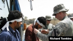 An ID card is placed around the neck of an Iraqi being released from a U.S. detention center prior to a reconciliation ceremony. In his hand is the Koran. There are slightly more than than 10,000 Iraqis in U.S. custody.