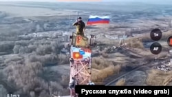 A Russian soldier hoists the Russian flag over Malaya Loknya in the Kursk region.