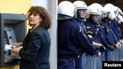 A woman makes a bank transaction during an Athens rally against austerity measures in Greece.