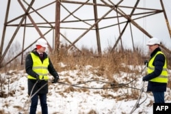 Министр энергетики Латвии Каспарс Мелнис и руководитель латвийского оператора электросетей AST Роландс Ирклис держат в руках перерезанную проволоку, соединявшую балтийскую сеть с российской