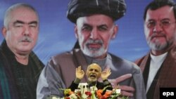 The "new" Ashraf Ghani speaks to supporters during a campaign rally in Kabul on March 9, against a backdrop of himself in conservative garb (center) and his vice-presidential running mates, Abdul Rashid Dostum (left) and Sarwar Danish.