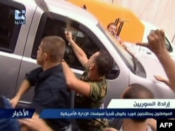 A TV video grab shows pro-regime supporters attacking a U.S. Embassy vehicle in Damascus on September 29.