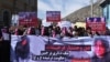 Members of the Afghan Solidarity Party wearing masks of the bloodied face of the woman who was lynched by a mob chant slogans during a protest against the attack in Kabul on March 23.