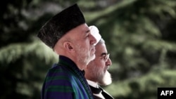 Afghan President Hamid Karzai (left) and Iranian President Hassan Rohani listen to their national anthems during a welcoming ceremony in Tehran in December.