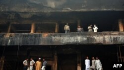 Pakistani shopkeepers stand on the balconies of their shops in a burned-out market in Karachi on December 30.