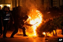 Police attempt to extinguish a fire as supporters of Calin Georgescu protested after in Bucharest.