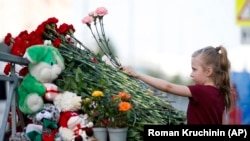 A young girl lays flowers at an impromptu shrine to victims of a deadly school shooting that took place in Tatarstan's capital, Kazan, earlier this week. 