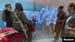 Members of Taliban forces gather and look at a poster of their reclusive leader, Mullah Mawlawi Haibatullah Akhundzada, shortly after the militant group's takeover of Kabul in August. 