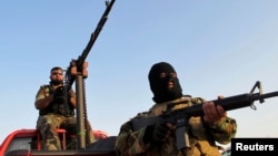 Armed Shi'ite volunteers from brigades loyal to radical cleric Muqtada al-Sadr take up positions with their weapons on a vehicle during a patrol on the outskirts of Samarra.