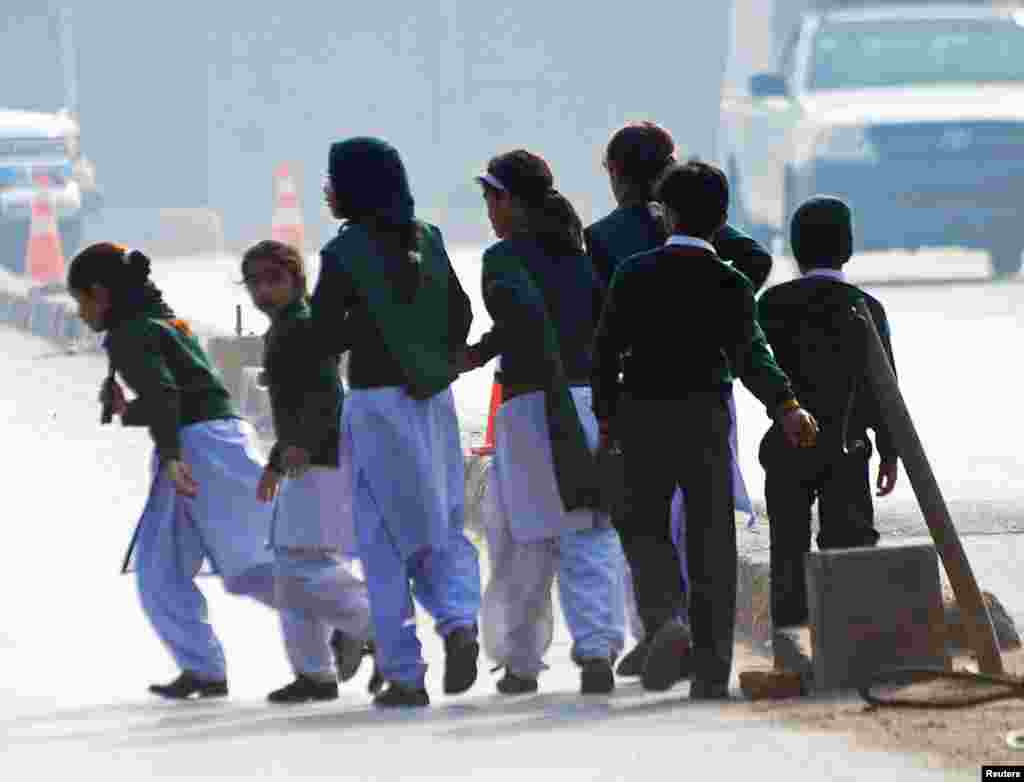 Schoolchildren cross a road as they move away from the military school.